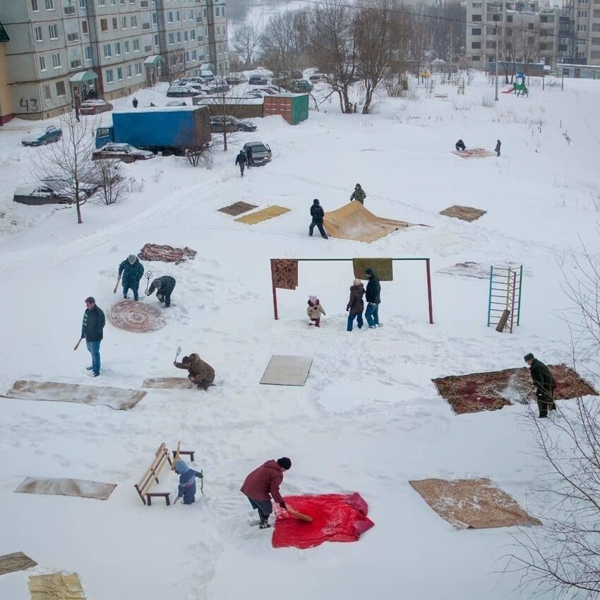 Люди чистят ковры на снегу