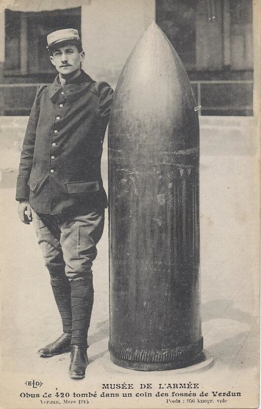 Французский солдат стоит рядом с неразорвавшимся 420-мм снарядом, упавшим на Верден. Март 1916 года. Он весил 2100 фунтов (952 килограмма)