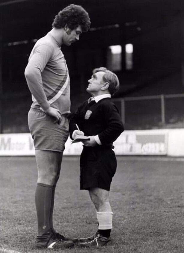 Футбольный арбитр Джоуи Шаклфорд (рост 1,46 м) выносит предупрeждение игроку Клайву Годдарду (рост 2,06 м). Англия, 1980 год