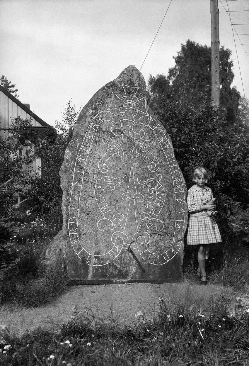 Девушка с плюшевым мишкой у рунного камня в Седербю, Боткирка. Надпись гласит: «Сиббе и Тьярве воздвигли камень в память об их отце Торкеле».