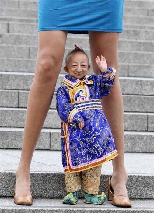 Хе Пингпинг из Монголии – самый маленький человек в мире (его рост 74,61 см) – стоит между ног Светланы Панкратовой – женщины с самыми длинными ногами. Ноги Панкратовой официально составляют 131,83 см.