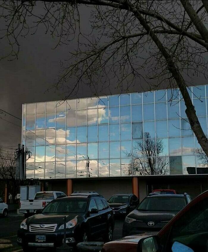 10. Голубое небо отражается в стеклянном здании, а позади - грозовая туча