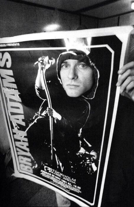 Курт Кобейн выглядывает сквозь плакат Брайана Адамса в Стокгольме. 1991 г.