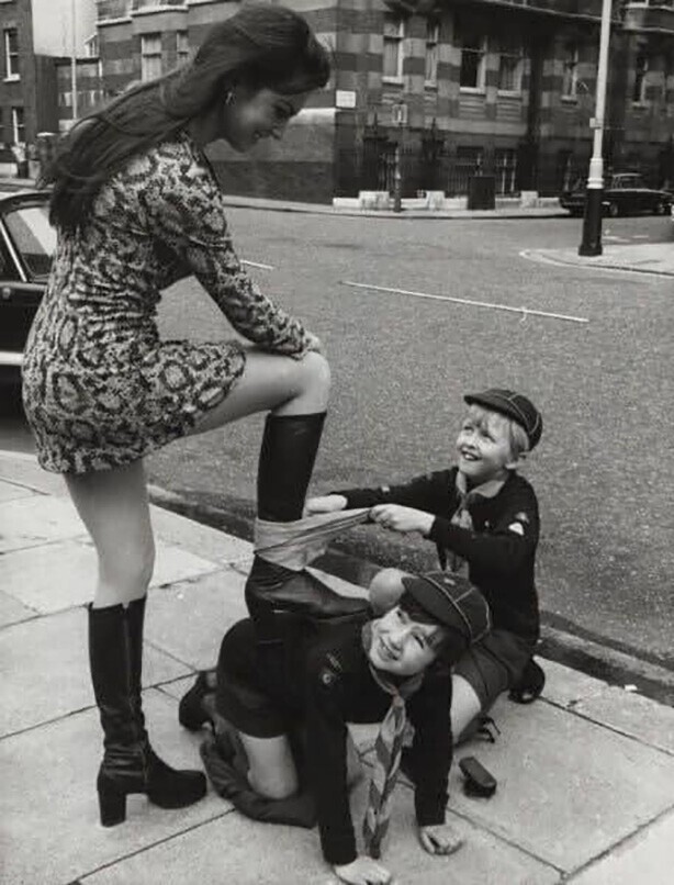 Два счастливых бойскаута полируют сапоги британской модели и актрисе Кэролайн Манро, 1973 год.