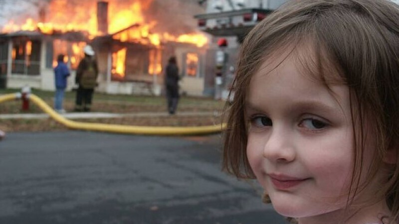 На оригинальной фотографии, о которой идет речь, молодая девушка с улыбкой позирует перед горящим зданием