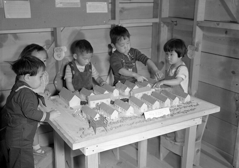 Дети интернированных японцев играют макетами своих бараков в центре перемещения «Tule Lake». США, штат Калифорния, 11 сентября 1942 года
