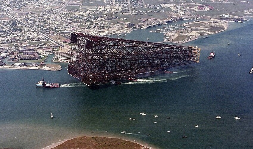 Буксировка нефтяной платформы в Мексиканский залив, на фоне прибрежных построек