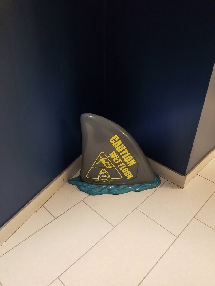 Табличка, предупреждающая о том, что пол мокрый, в виде акульего плавника