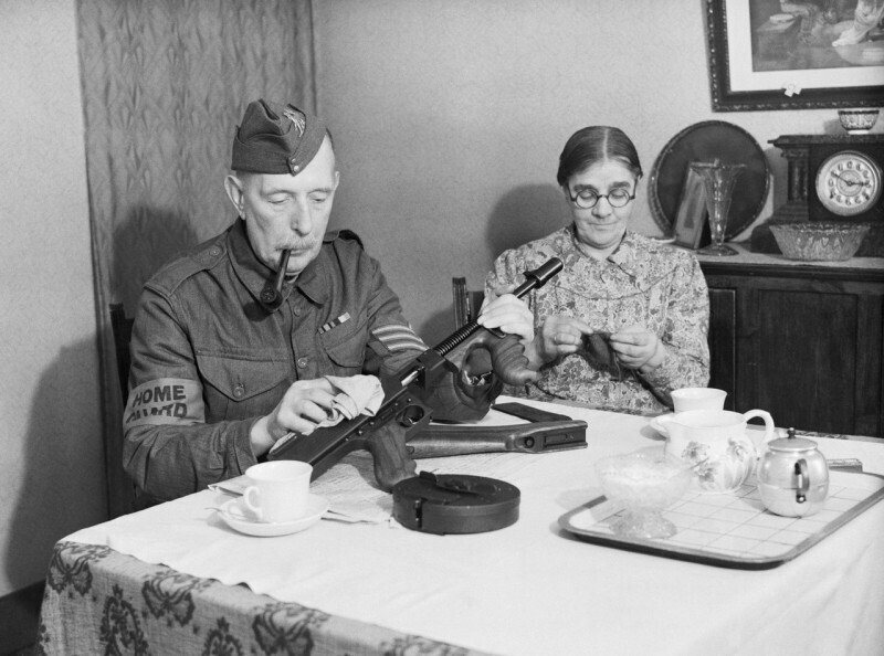 Пожилой сержант Войск Местной Обороны чистит за обеденным столом свой пистолет-пулемёт Thompson M1928. Доркинг. Графство Суррей. Великобритания. 1 декабря 1940 года.