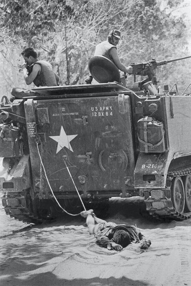 Американские военные волокут на привязи тело вьетконговского (южновьетнамский повстанец) солдата. Южный Вьетнам, 24 февраля 1966 года