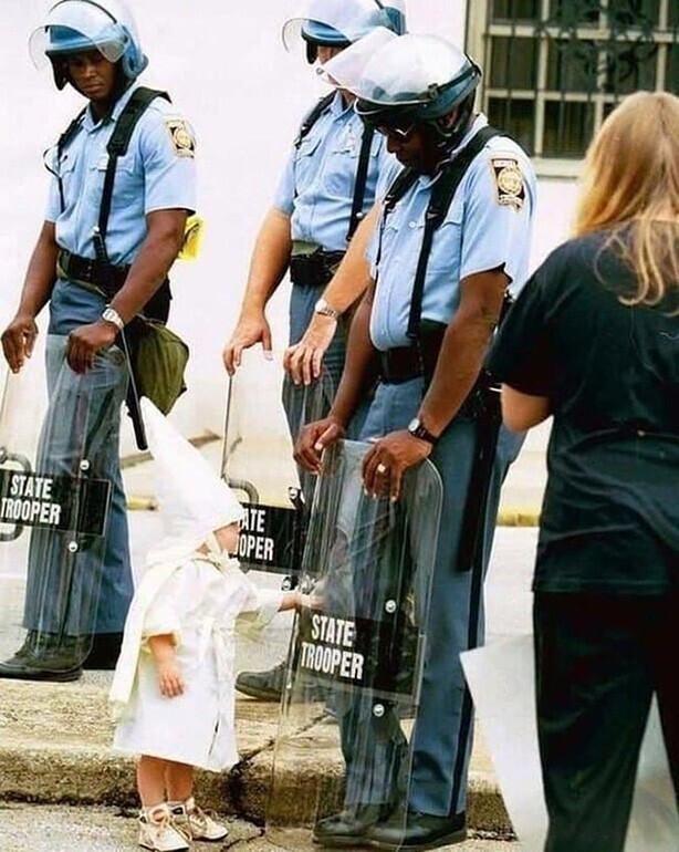 Маленький белый ребёнок трогает защитный щит темнокожего полицейского во время митинга Ку-клукс-клана в Гейнсвилле, штат Джорджия, 1992 год