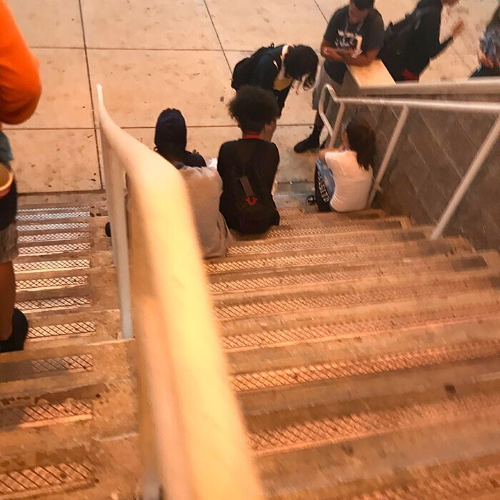 Молодежь, которая сидит на лестницах, путаясь под ногами у прохожих