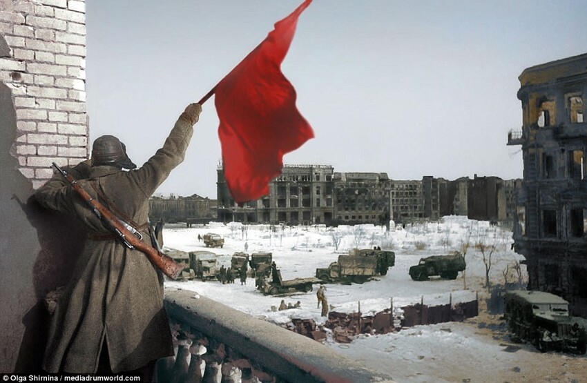 Во время Сталинградской битвы советский солдат машет флагом с балкона, который выходит на площадь.