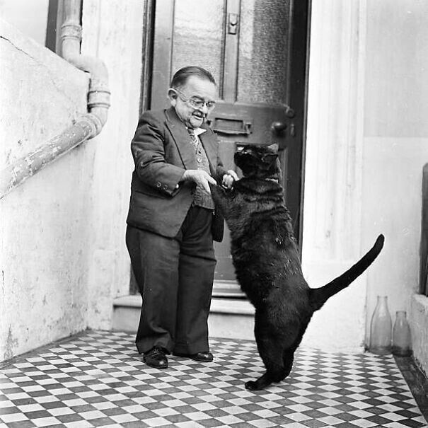 Британец Генри Беренс (1890 - 1938), который считался самым маленьким человеком в то время, танцует со своим котом возле своего дома