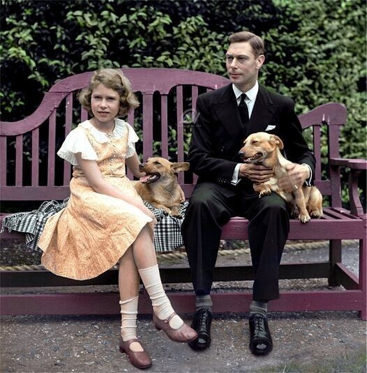 Король Георг VI и принцесса Елизавета сидят на скамейке со своими собаками корги на территории своего лондонского дворца. Великобритания. Июль 1936 г.