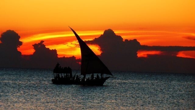Силуэт туристической лодки на фоне заката.