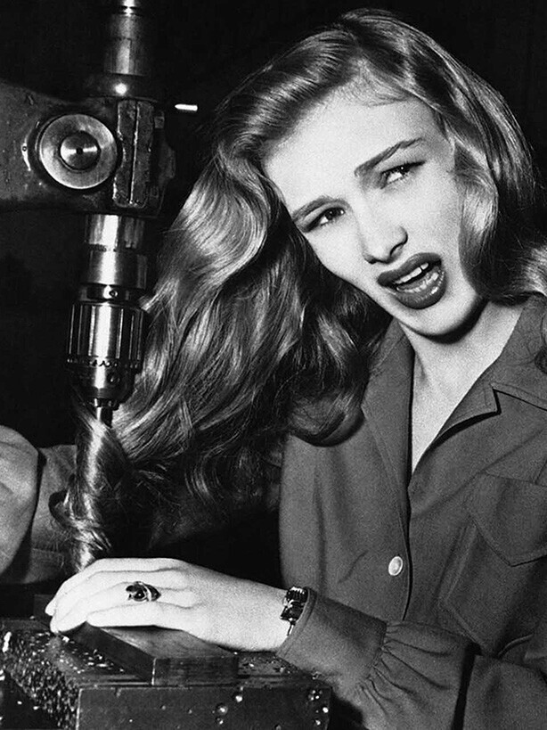 Американская киноактриса Вероника Лейк иллюстрирует, что может случиться с женщинами-военщинами, которые носят длинные волосы во время работы на станках на фабрике где-то в Америке 9 ноября 1943 года.