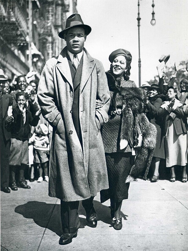 Чемпион в супер тяжелом весе Джо Луис и его жена гуляют по Гарлему, штат Нью-​Йорк, на следующий день после того, как Луи победил бывшего чемпиона Макса Бэра на стадионе Янки в 1935 году.