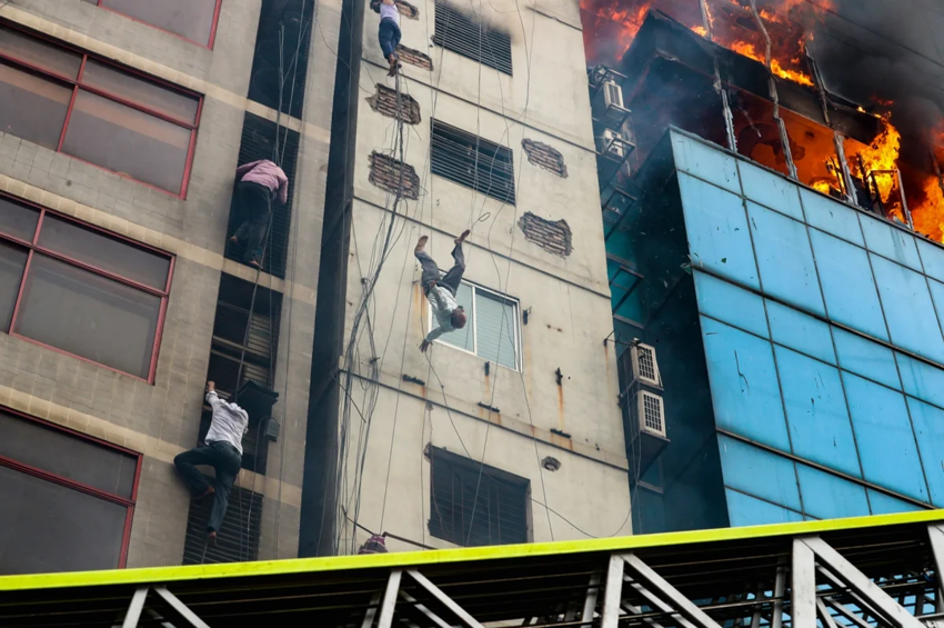 Мужчина пытается спастись во время пожара в Дакке, в результате которого 25 человек погибли, 70 получили ранения, а 22-этажное здание было разрушено. Мужчина опускался, держась за трос, но жара заставила его внезапно отпустить руки, и он рухнул на зе