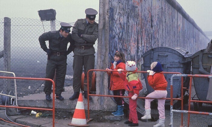 14. Западногерманские школьники общаются с двумя восточногерманскими пограничниками у проема в Берлинской стене в ноябре 1989 года (Фото: Стивен Яффе)