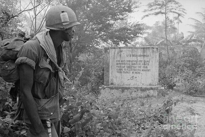 19. Чернокожий солдат армии США читает сообщение, оставленное Вьетконгом во время войны во Вьетнаме