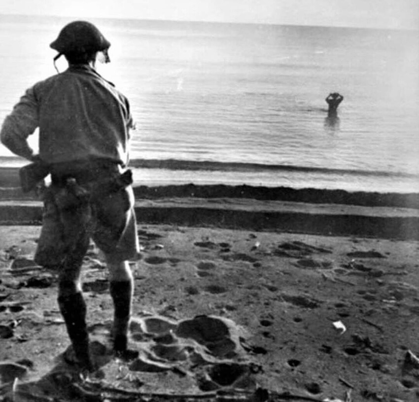 Японский солдат, чтобы избежать плена, зашел в море, где собирается покончить жизнь самоубийством, взорвав гранату у своей головы, за этим действием наблюдает австралийский солдат, Новая Гвинея. 18 декабря 1942 года