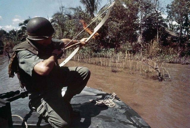 6. Коммандер-лейтенант Дональд Д. Шеппард стреляет горящей стрелой в бамбуковую хижину во Вьетнаме (1967 год)