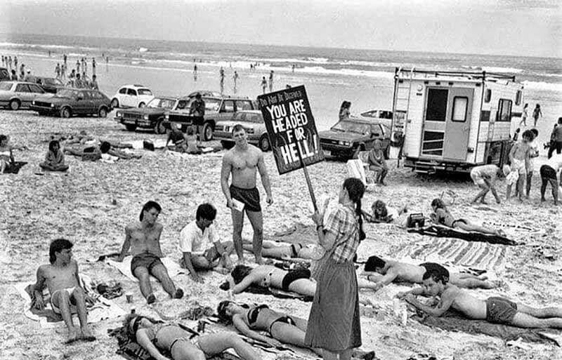 16. Пуританка протестует против откровенных купальников на пляже во Флориде; надпись на плакате: "Вы все направляетесь в ад" (1985 год)