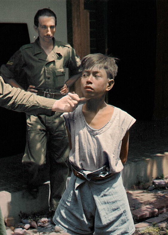 Голландские солдаты допрашивают индонезийского мальчика из партизанского отряда во время Войны за независимость Индонезии, примерно 1945-1950 гг.
