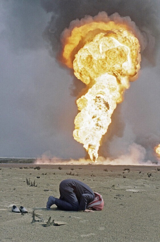 Кувейтский нефтяник во время полуденной молитвы возле горящего нефтяного месторождения недалеко от города Кувейт, 2 марта 1991 года