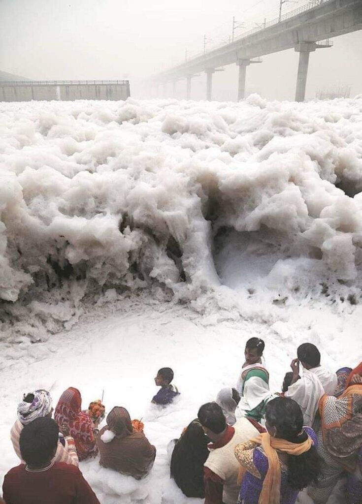Люди возносят молитвы на индийской реке Ямуна, вспененной из-за промышленных отходов