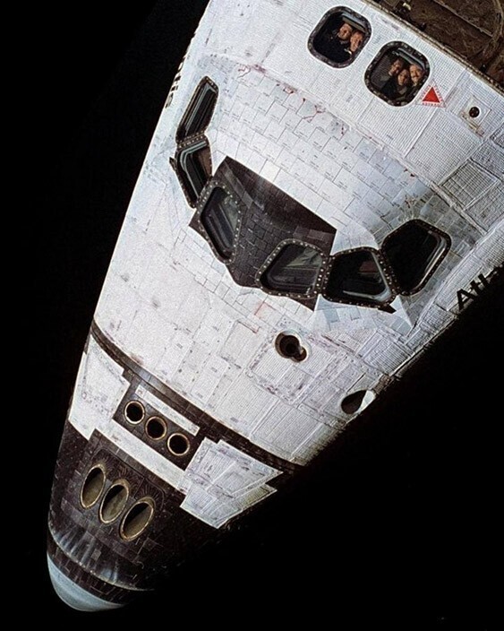 Снимок астронавтов в иллюминаторе шатла, сделанный со станции “Мир“