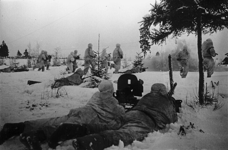Автоматчики 1-го Прибалтийского фронта, одетые в зимние маскхалаты, в наступлении. На переднем плане расчет пулемета «Максим».