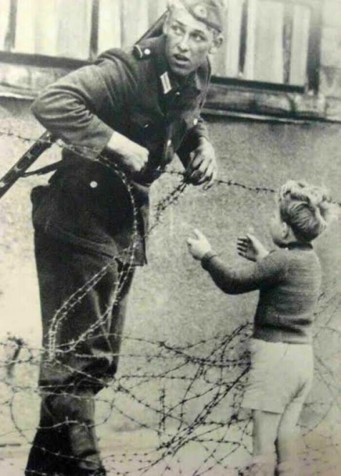 4. Немецкий солдат помогает маленькому мальчику перебраться через Берлинскую стену, 1961 год