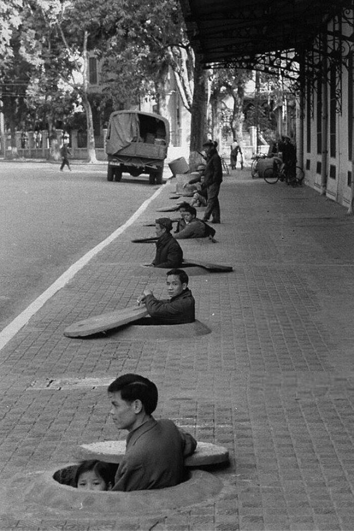 35. Жители Ханоя в убежищах на тротуаре ждут отбоя воздушной тревоги. Ханой, Северный Вьетнам, 1967 год