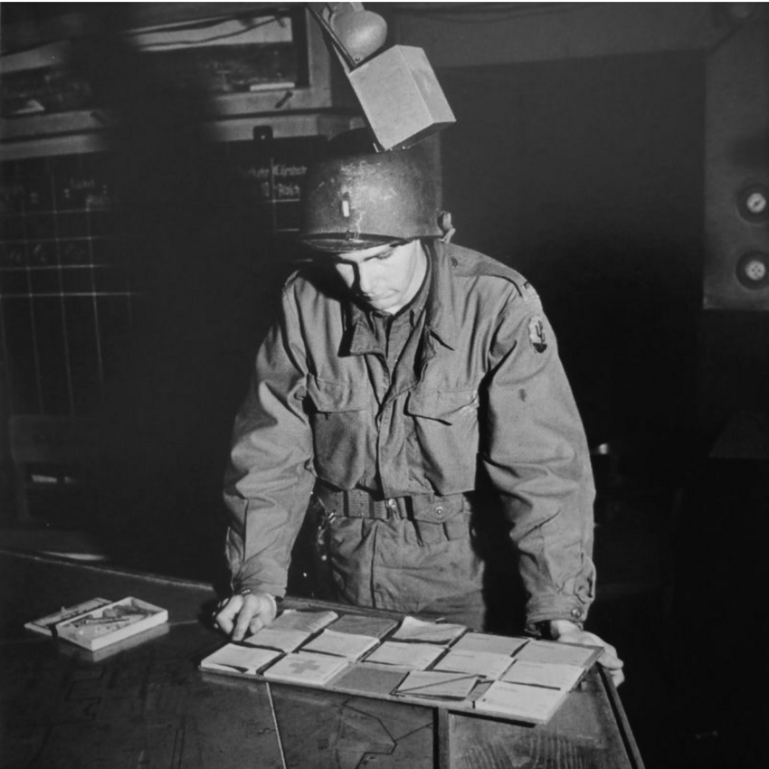 Американский офицер смотрит на бланки документов, найденных на заводе в Людвигсхафене