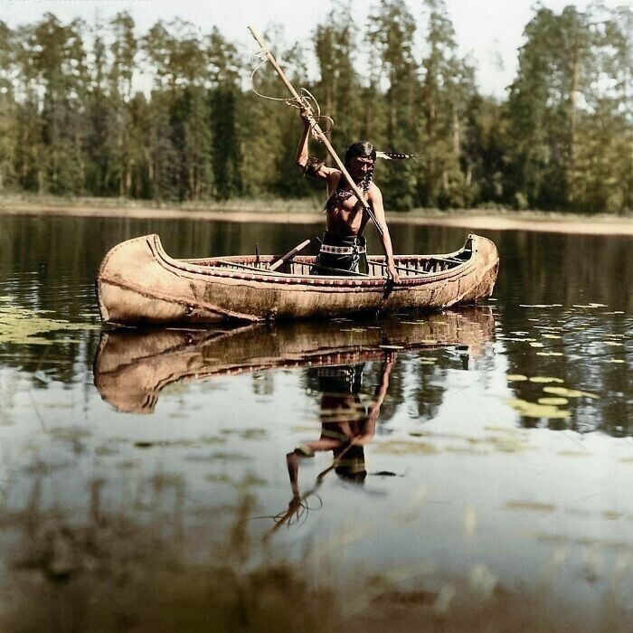 7. Индеец оджибве ловит рыбу с помощью гарпуна где-то в Миннесоте, США. Фотография сделана в 1908 году