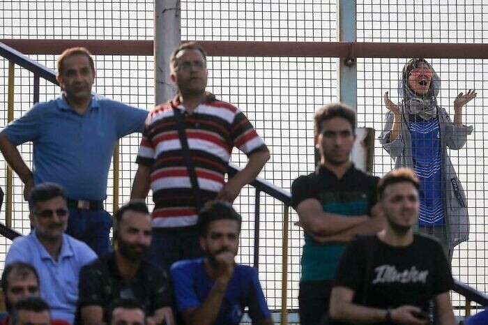 10. "Иранская девушка болеет за свою любимую футбольную команду из-за забора, поскольку иранских женщин не пускают на стадионы"