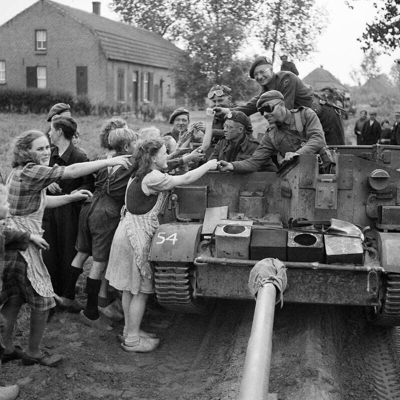 23. Британские солдаты раздают шоколад жителям Нидерландов во время наступления 11-й бронетанковой дивизии 22 сентября 1944 года