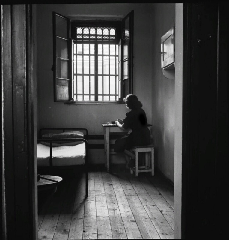 Тюрьма для малолетних преступников. Молодая проститутка в своей камере у открытого окна. Надпись на двери ее камеры гласит: «Венерические заболевания — заразная». Австрия, Вена, 1948 год