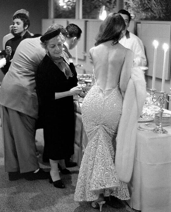 Пожилая женщина рассматривает откровенное платье актрисы Викки Дуган на фуршете, Лос-Анджелес, США, 1957 год.