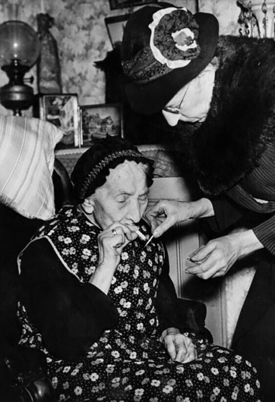 75-летняя Мэри Пэриш прикуривает сигарету для ее 101-летней матери. Лондон, 1946 год