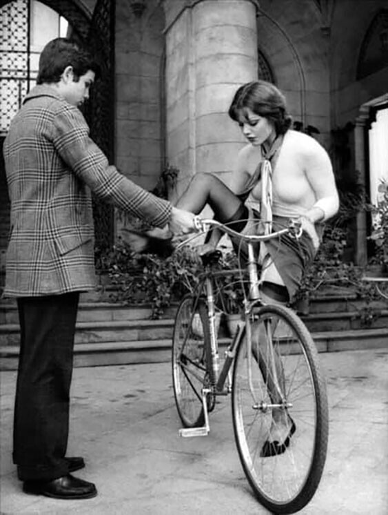 Молодой человек галантно помогает даме взобраться на велосипед. Италия, 1973 год