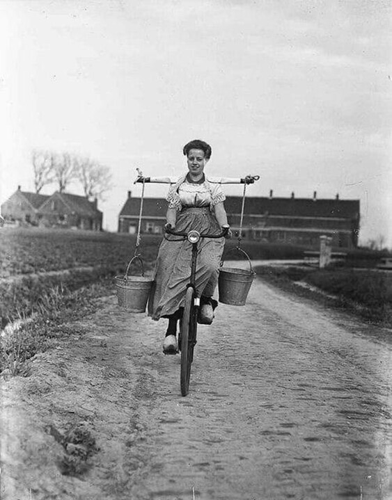 Крестьянка с ведрами молока на коромысле на велосипеде. Нидерланды, 1946 год