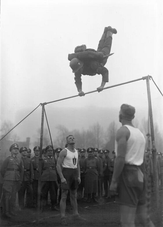 Немецкий солдат выполняет упражнение на турнике в полной экипировке, 1934 год