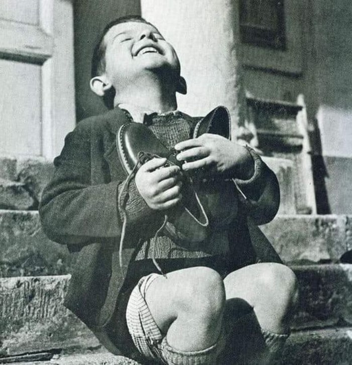35. 6-летний австриец сияет безграничной радостью, получив новую пару обуви от Красного Креста в конце Второй мировой войны, 1945 год