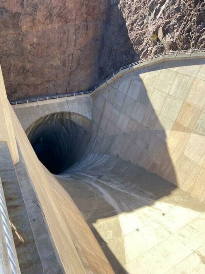 34. Водосбросный туннель плотины Гувера, 15 метров в ширину и 183 в глубину. Можно услышать, как в темноте бежит вода. Дорожка с перилами выше наглядно демонстрирует масштаб