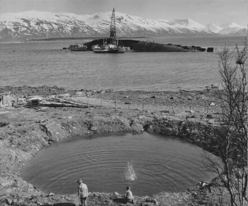 Норвежские дети играют у воронки от бомбы "Tallboy" на фоне затонувшего линкора «Тирпиц»