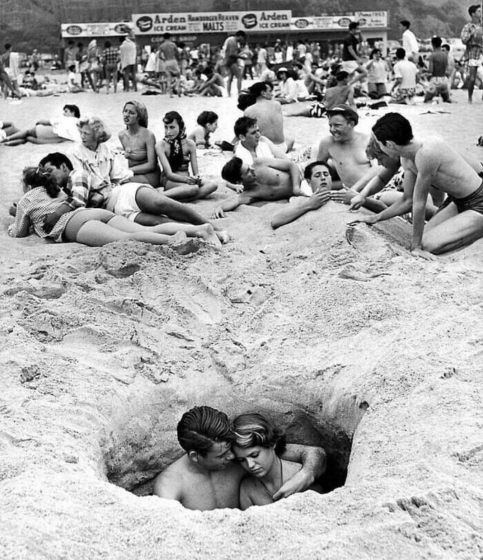 Пара наслаждается относительным уединением, обнимаясь в песчаной норе на пляже в Санта-Монике, Калифорния, 4 июля 1950 года