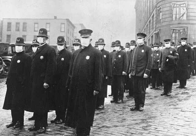 Полицейские стоят на улице в Сиэтле, штат Вашингтон, в защитных масках, изготовленных Сиэтлским отделением Красного Креста, во время эпидемии гриппа в 1918 году